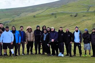 A group of nineteen men out on a walk in the countryside