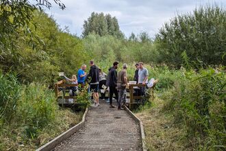 A group of children and adults on the pond dipping platform at Low Hall Nature Reserve in Wigan 