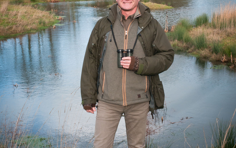 Simon King standing in front of a pond