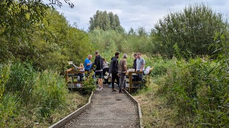 A group of children and adults on the pond dipping platform at Low Hall Nature Reserve in Wigan 
